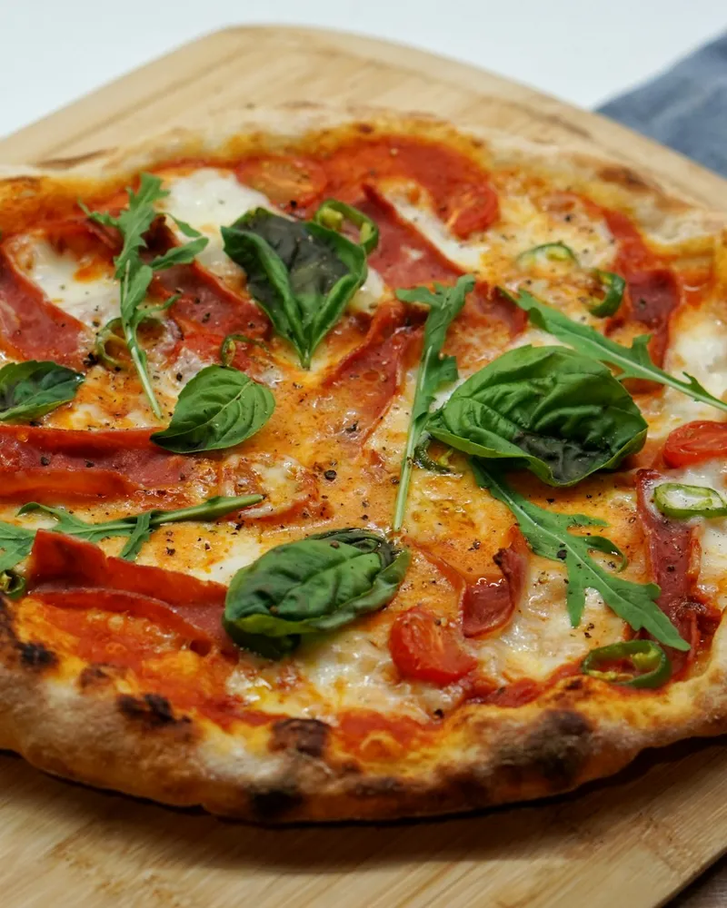 Pinsa mit Tomatensauce und frischen grünen Blättern
