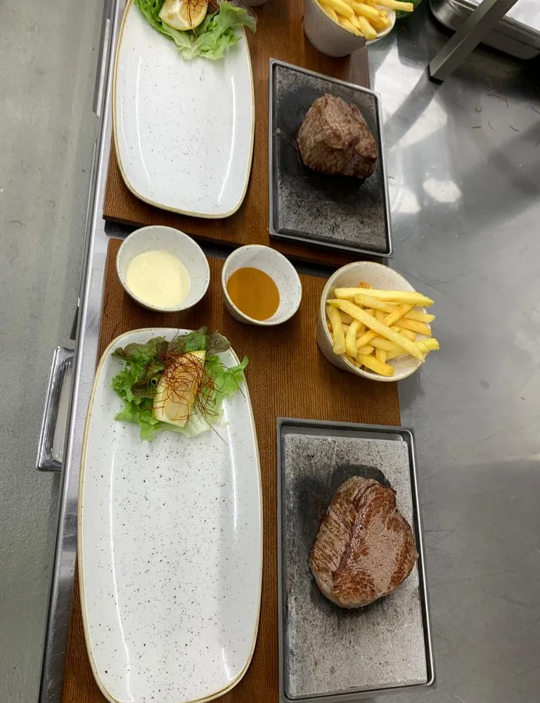 Zwei Steaks mit Pommes frites und Saucen auf dem Küchenpass